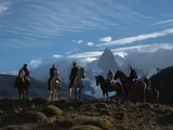 Grupo a caballo con baqueanos en una loma frente al Cerro Fitz Roy, en Estancia Bonanza