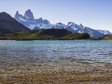 Crystal clear water of Laguna Capri with the Fitz Roy mountain range on the horizon
