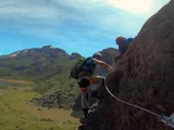 Participants secured to the lifeline ascending the via ferrata above the valley
