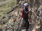 Two participants wearing helmets advancing along the metal rungs of the via ferrata