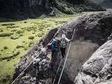 Group crossing a traverse with steel cables on the Estancia Bonanza via ferrata, with the valley in the background